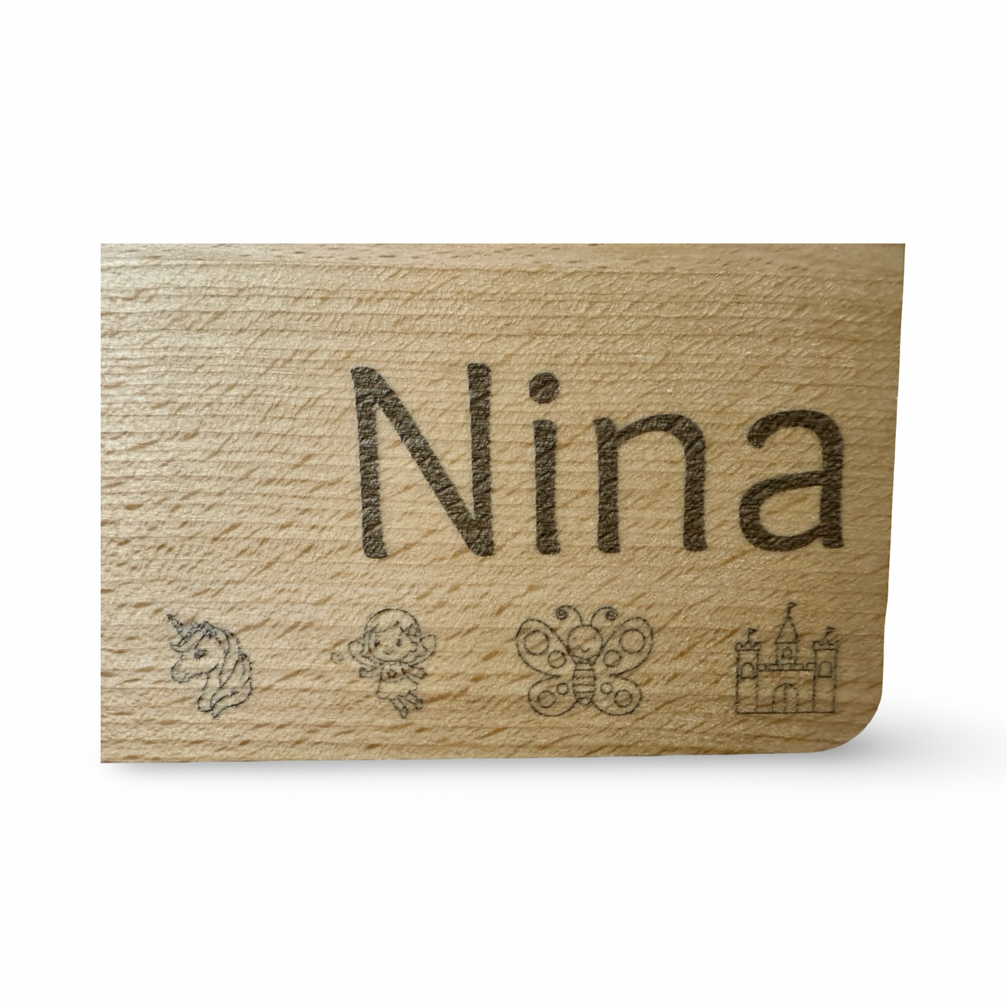 Detailansicht der Gravur eines personalisierbaren Kinder-Frühstücksbrettes aus Holz mit Lasergravur „Nina“ und niedlichen Motiven wie Einhorn, Elfe, Schmetterling und Schloss