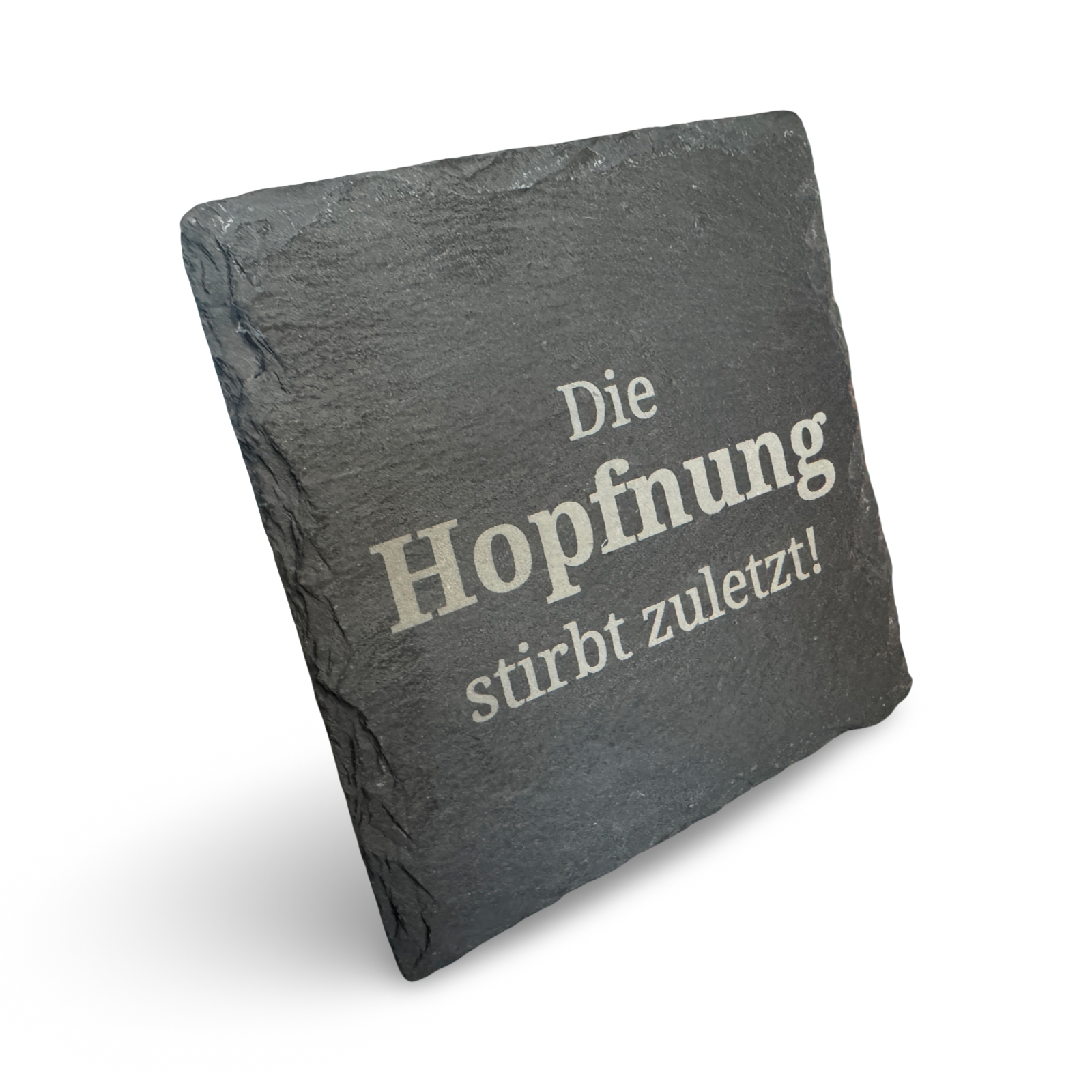 Schräge Ansicht eines Untersetzers aus Schiefer mit lasergraviertem Schriftzug „Die Hopfnung stirbt zuletzt"  – dekorativer Getränkeuntersetzer für Bierliebhaber
