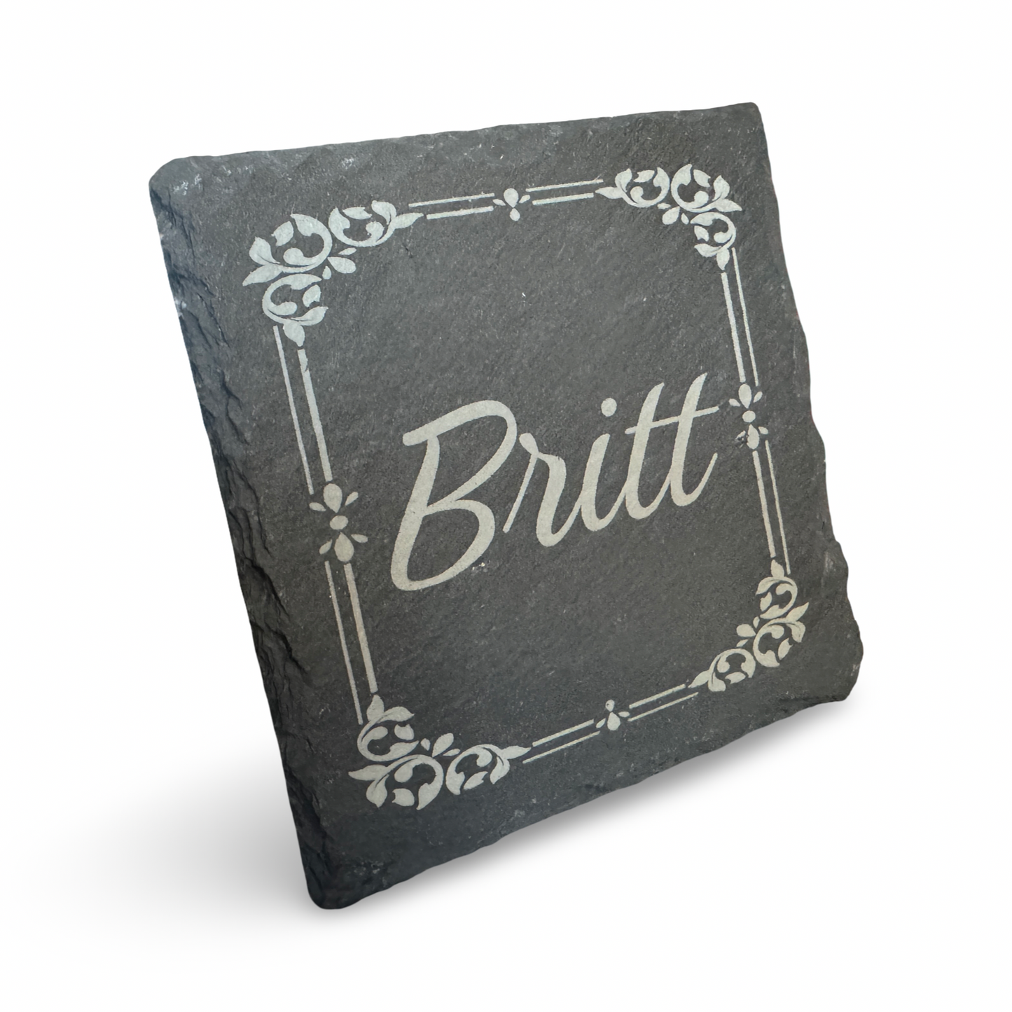 Schräge Ansicht eines Untersetzers aus Schiefer mit lasergraviertem Schriftzug „Britt"  – individualiserbarer Name - dekorativer Getränkeuntersetzer