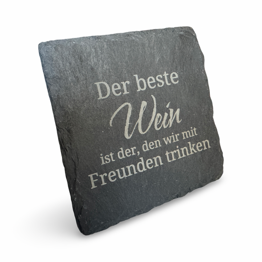 Schräge Ansicht eines Untersetzers aus Schiefer mit lasergraviertem Schriftzug „Der beste Wein ist der, den wir mit Freunden trinken“ – dekorativer Getränkeuntersetzer für Weinliebhaber